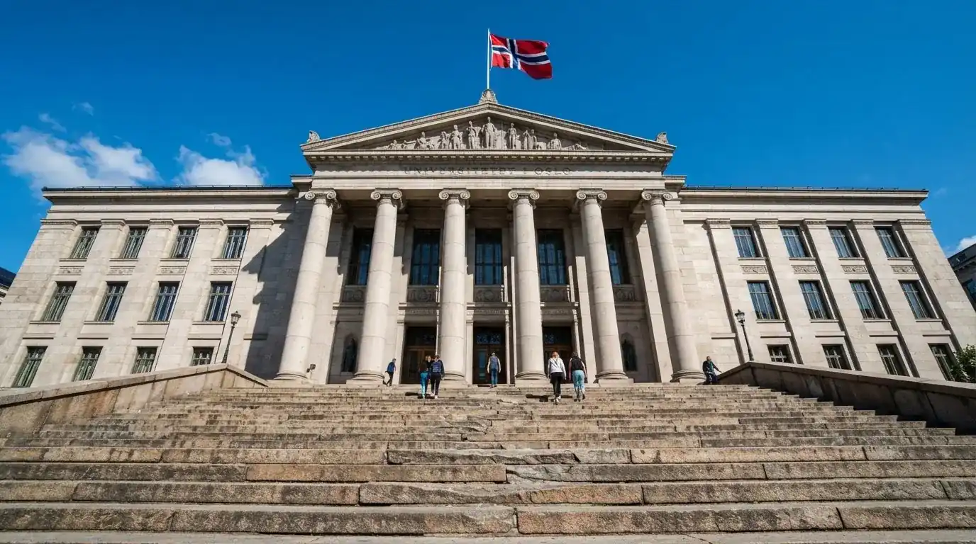 Bred granitttrapp foran en offentlig bygning med søyler og et flagg i vinden, blå himmel